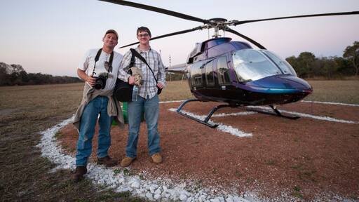 Male photographer and his son arrive by helicopter at Chitengo Camp inside Gorongosa National Park, Mozambique; Gorongosa National Park, Mozambique