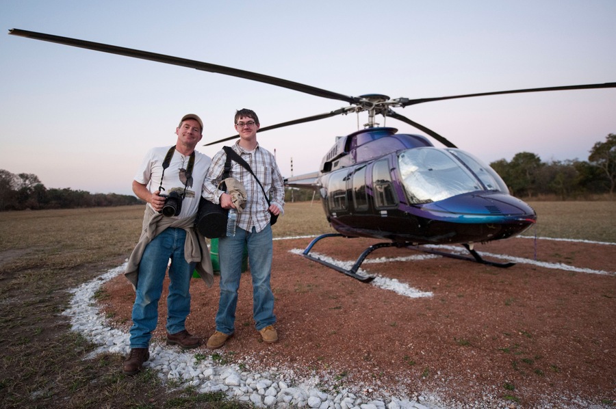 Male photographer and his son arrive by helicopter at Chitengo Camp inside Gorongosa National Park, Mozambique; Gorongosa National Park, Mozambique
