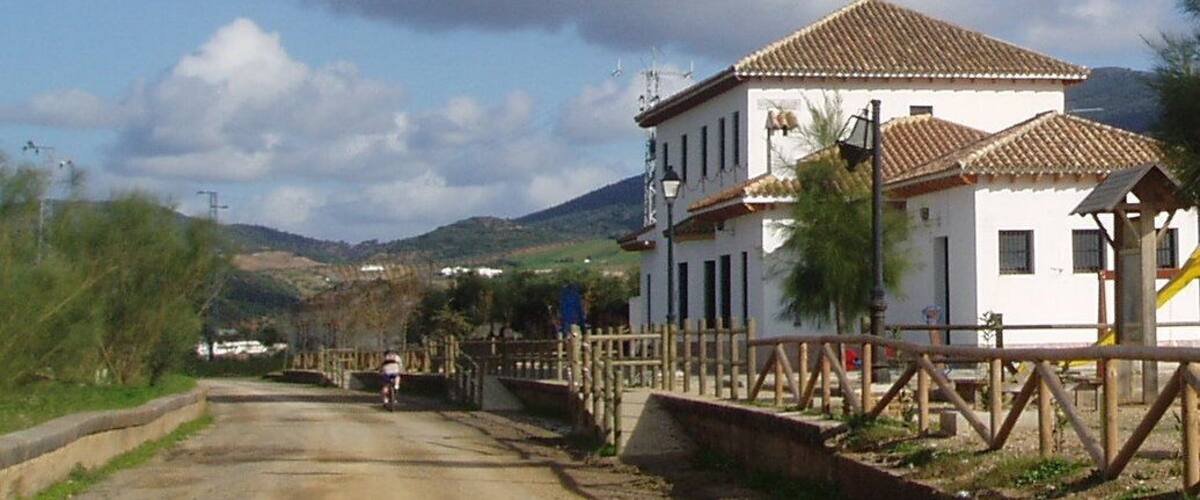 A rural road with a white house and a bridge.