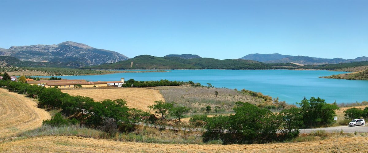 A lake surrounded by hills and wind turbines.