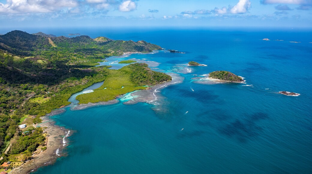 An aerial view of a coastal region with lush green hills, clear blue waters, and small islands.