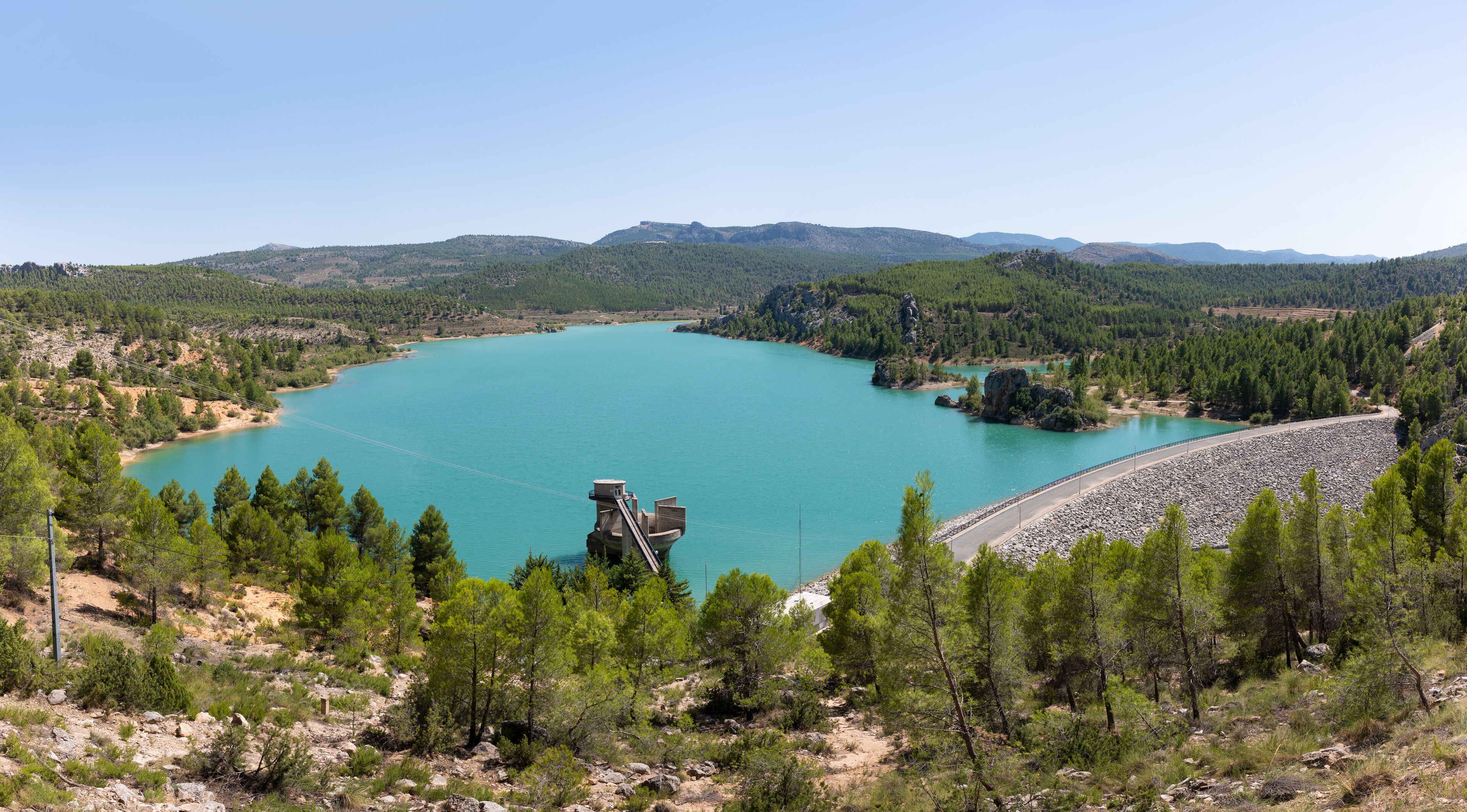 A view over the beautiful Taibilla reservoir in Kastillen in the sunshine. In the foreground the dam and technical systems and in the background a mountain landscape.