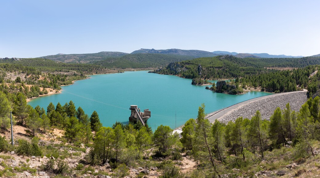 A view over the beautiful Taibilla reservoir in Kastillen in the sunshine. In the foreground the dam and technical systems and in the background a mountain landscape.