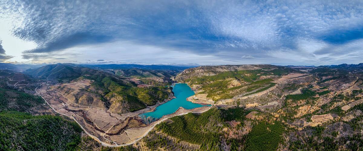A mountainous landscape with a turquoise lake surrounded by forested areas and terraced fields.