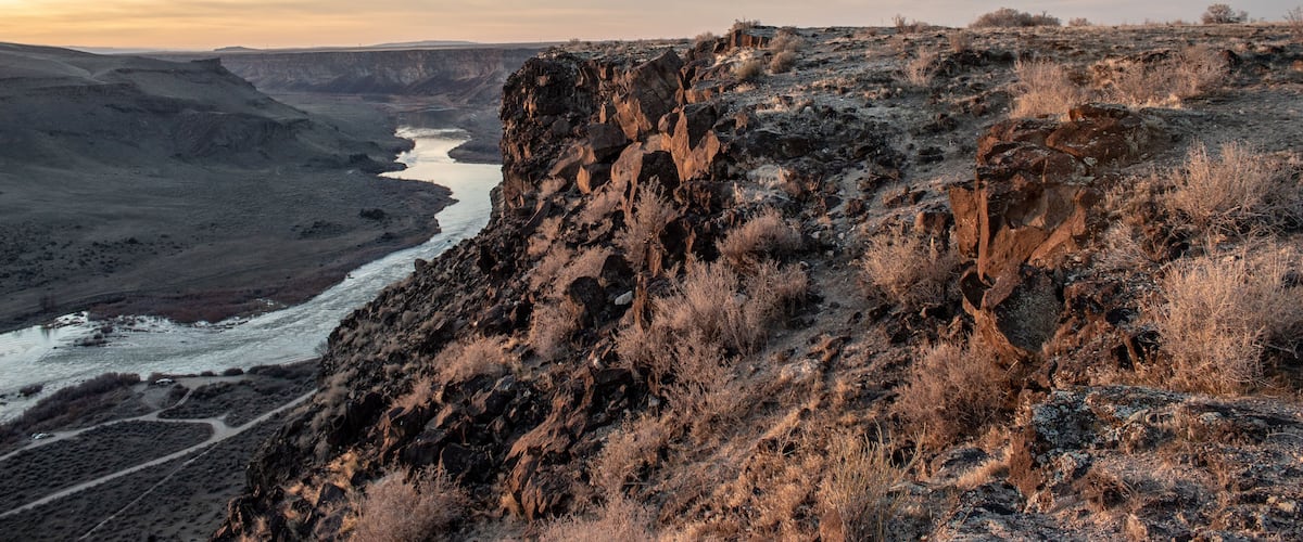 A rugged canyon landscape with a river flowing through it.