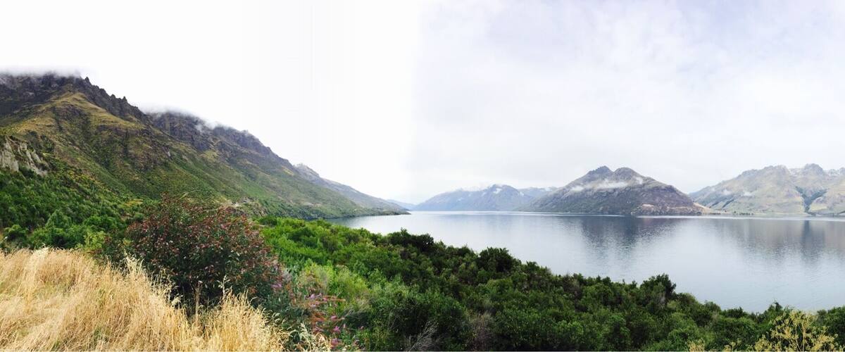 A calm lake surrounded by lush green hills and mountains.
