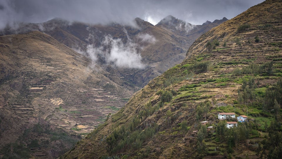 Terraced fields, a small village, and mountains with clouds.