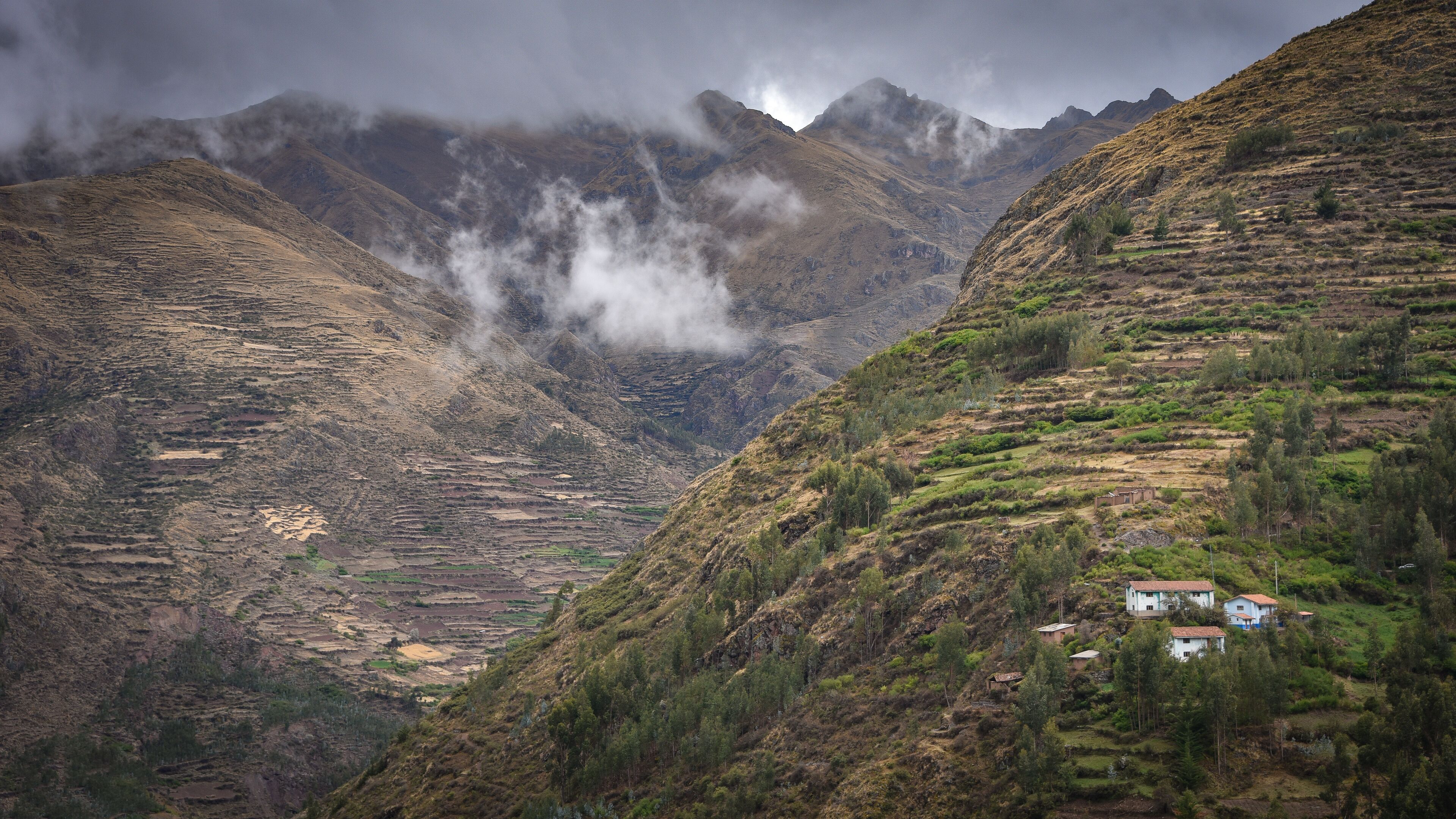 Terraced fields, a small village, and mountains with clouds.