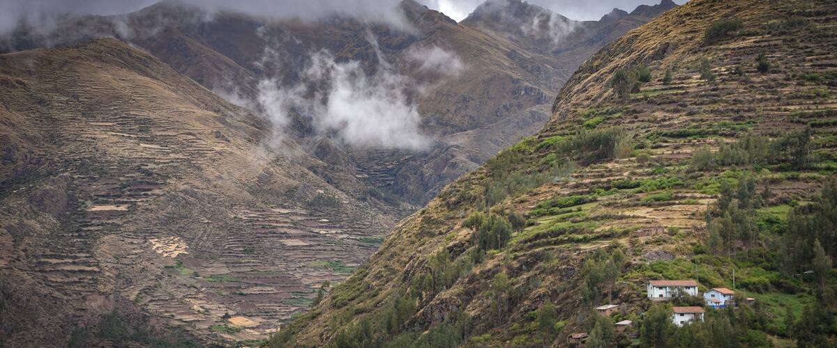Terraced fields, a small village, and mountains with clouds.