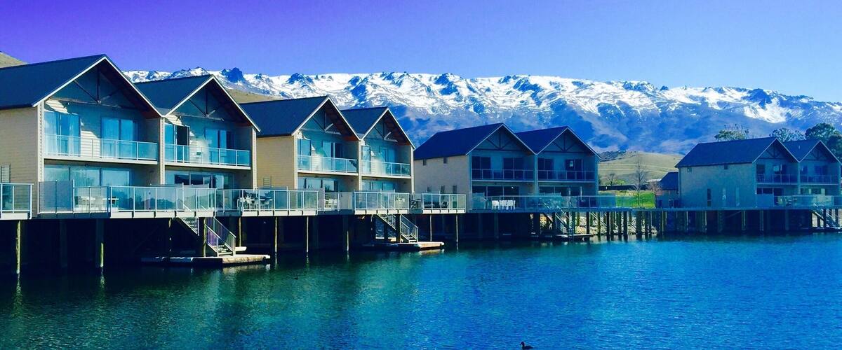 A row of modern waterfront homes with a mountain backdrop.
