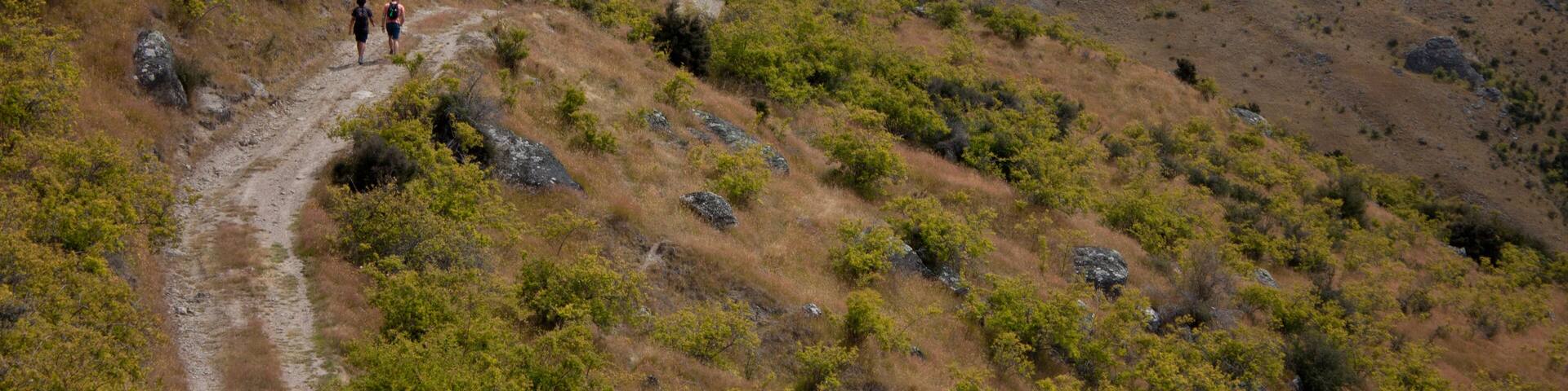 Two hikers in the distance on the way to Mt Pisa near Cromwell in New Zealand