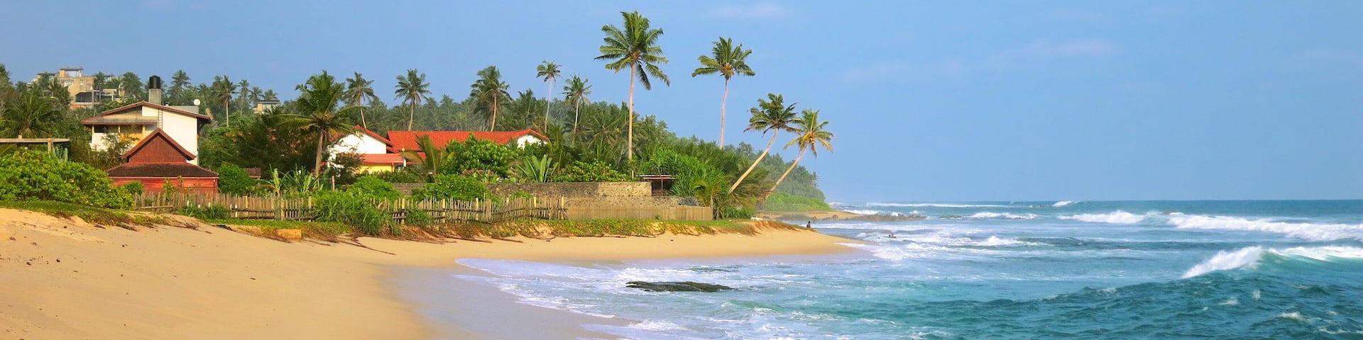 Empty sandy tropical beach with resort buildings, Kamburugamuwa, Sri Lanka