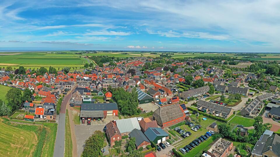 A town with red-roofed houses, a church, and surrounding fields.