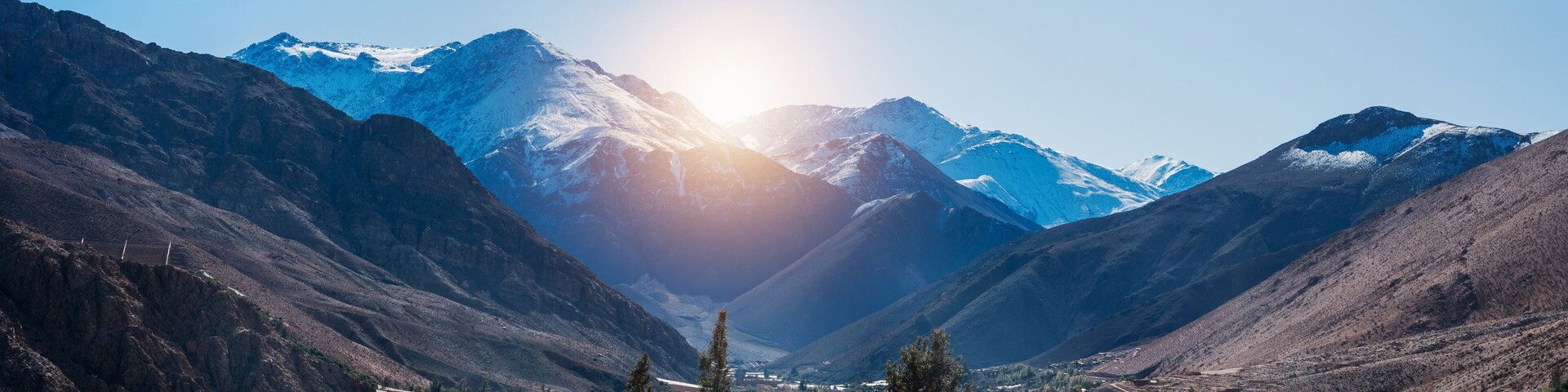 Un paisaje montañoso con un valle, un río y un pequeño asentamiento.