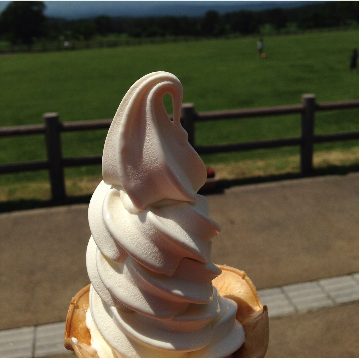 Cono de helado tipo soft serve con un remolino sobre una superficie de madera.