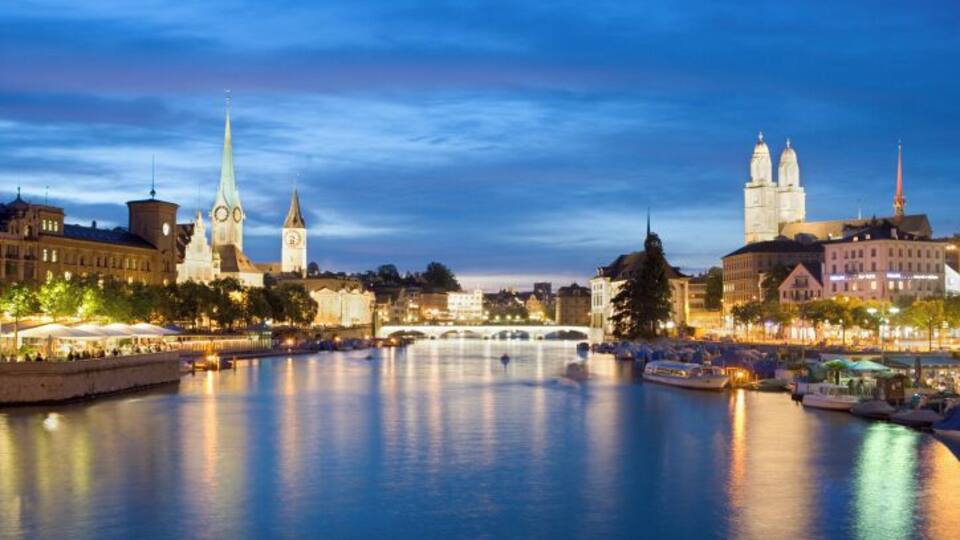 A river with boats, a clock tower, and a bridge.