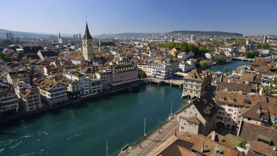 A river flowing through a city with historic buildings and a prominent clock tower.