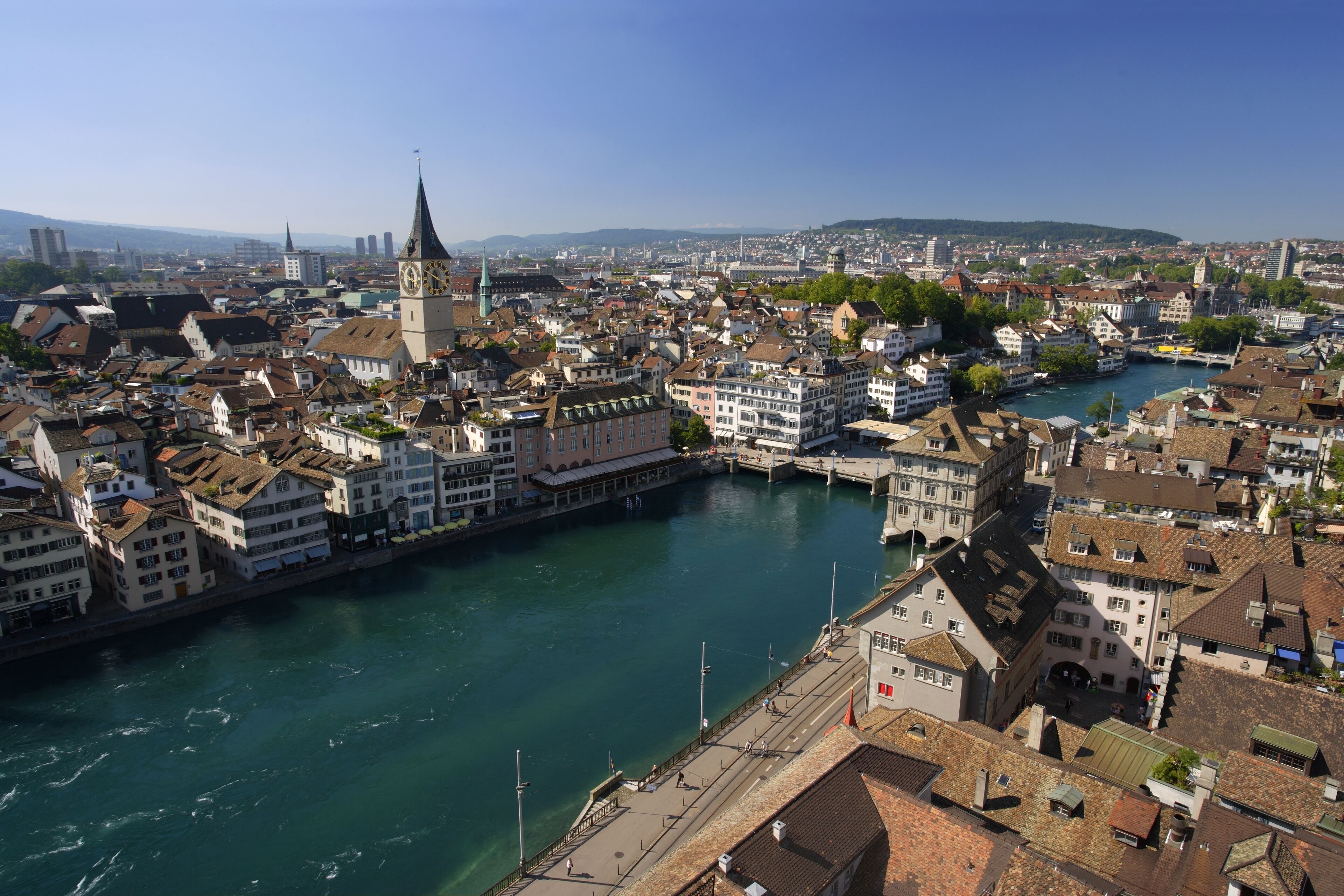 A river flowing through a city with historic buildings and a prominent clock tower.