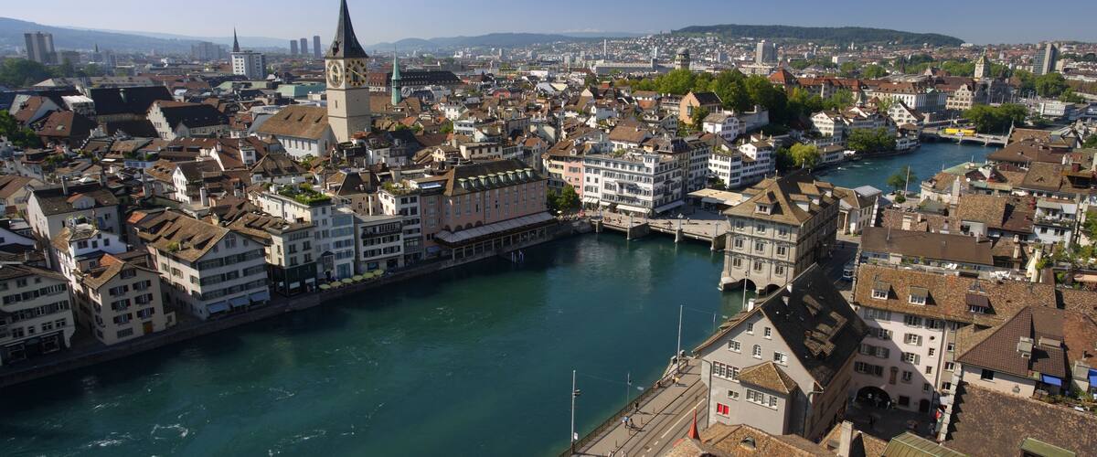 A river flowing through a city with historic buildings and a prominent clock tower.