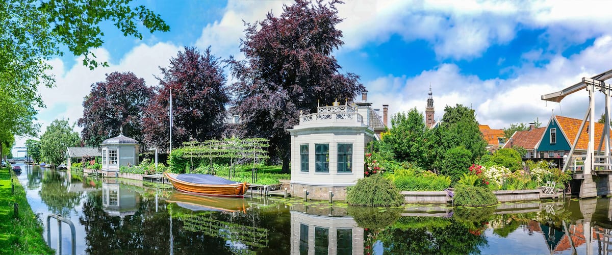 A canal with a boat, a white building, and a bridge.