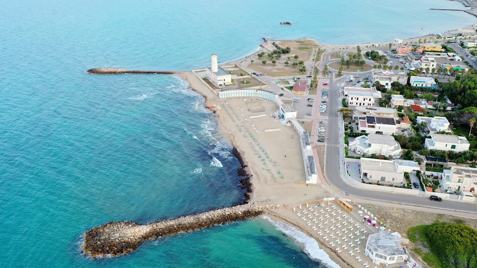 A coastal town with a lighthouse, beach, and residential area.