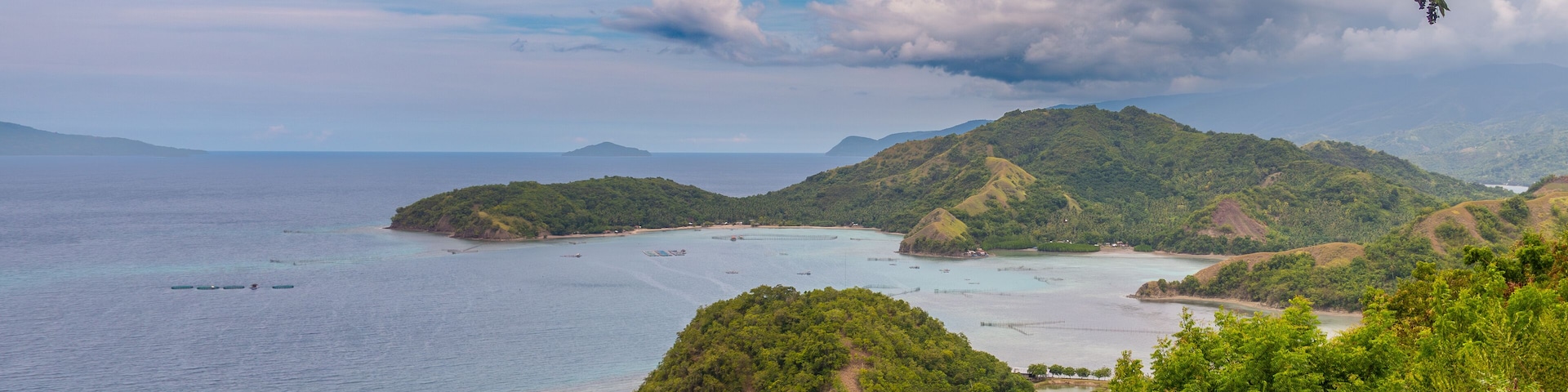 Un paisaje costero con colinas verdes exuberantes, aguas turquesas cristalinas y una pequeña isla.