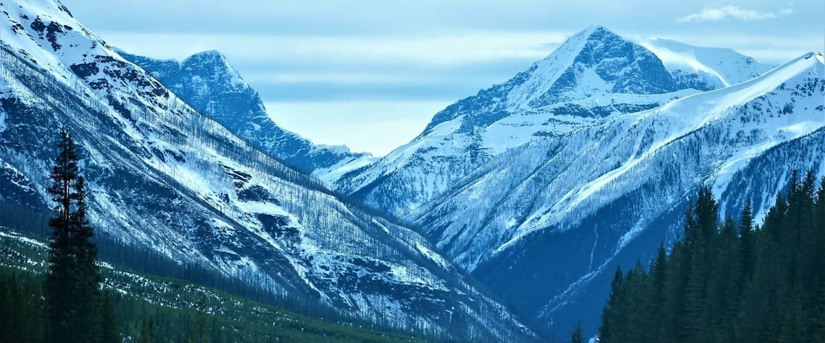 A snow-covered mountain road with a car driving towards a peak.