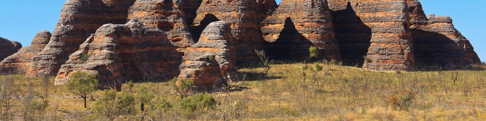A large rock formation with layered strata and a clear blue sky.