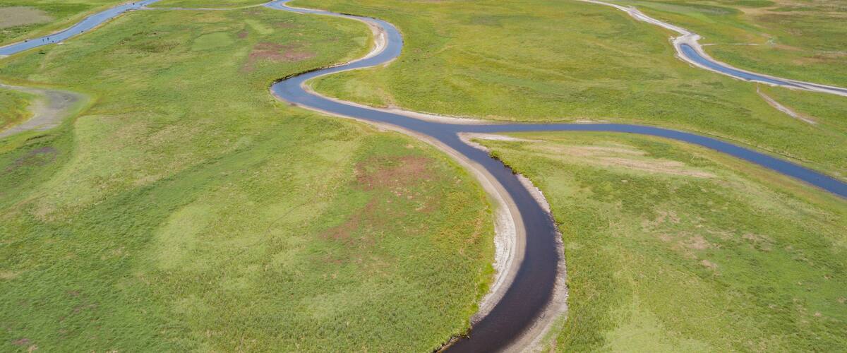 A winding river through a green landscape with multiple bends and a clear sky.