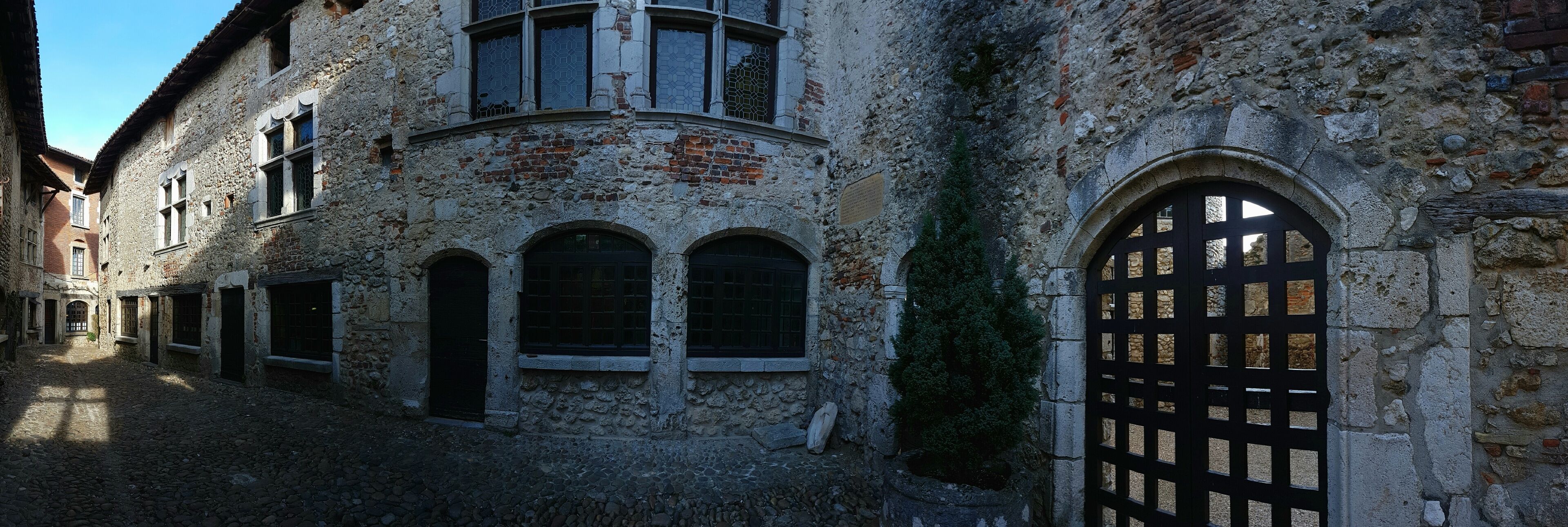 A historic stone building with arched windows and a cobblestone courtyard.