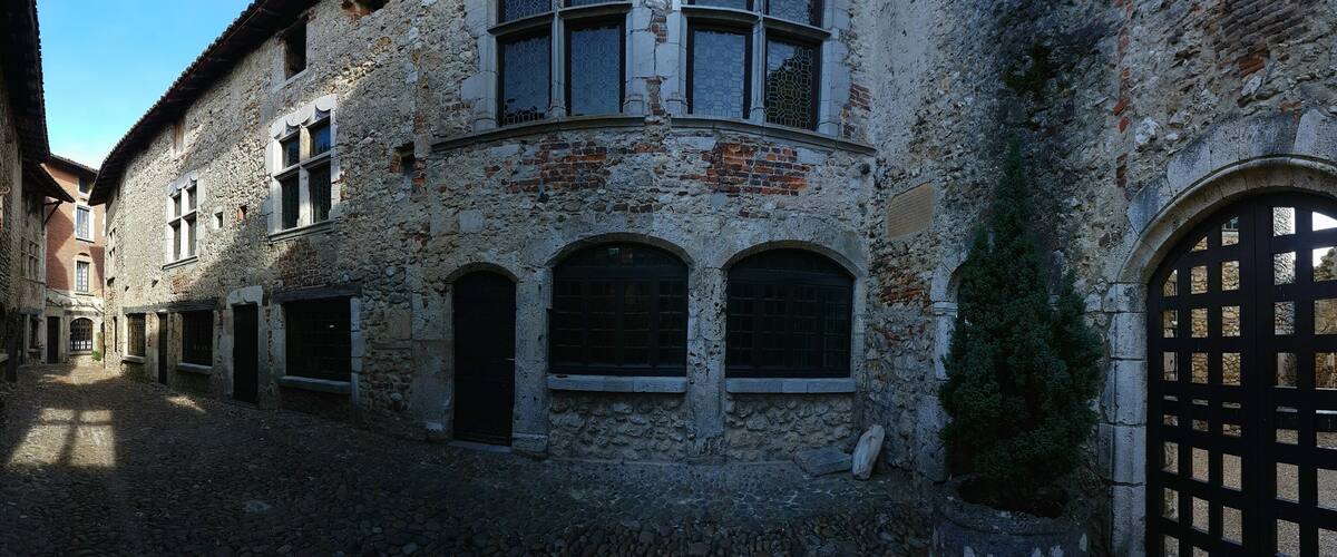 A historic stone building with arched windows and a cobblestone courtyard.