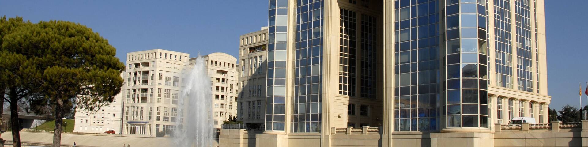 A modern building with large glass windows and a fountain in front.