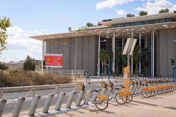 Un bâtiment moderne doté d’une conception de toit originale, d’une enseigne et d’une rangée de vélos garés.