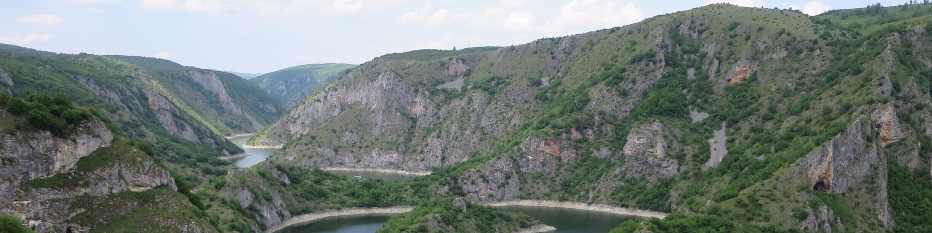 A river winding through a mountainous landscape with lush greenery and rocky cliffs.