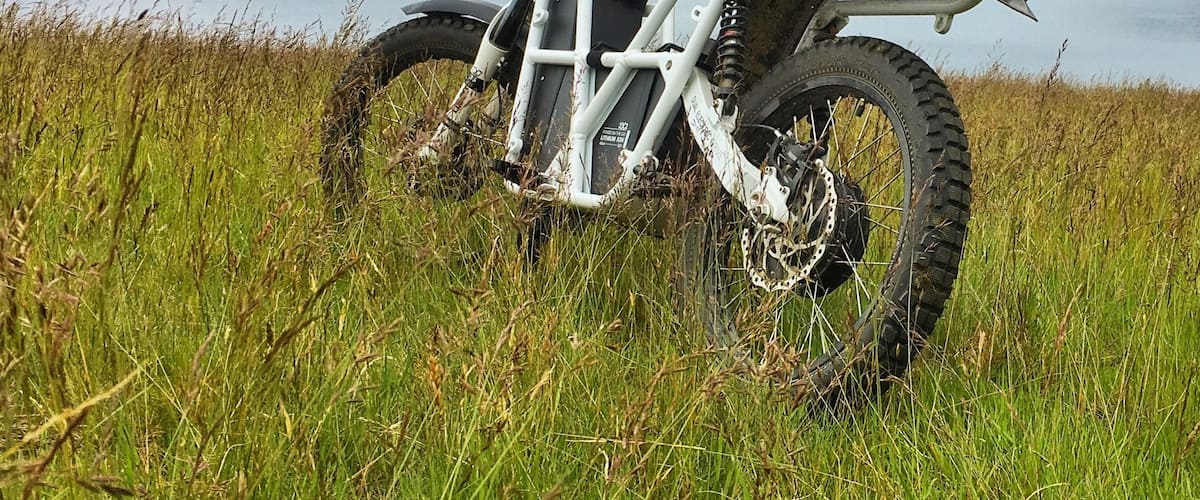 A white ATV parked on a grassy field with a lake and mountains in the background.