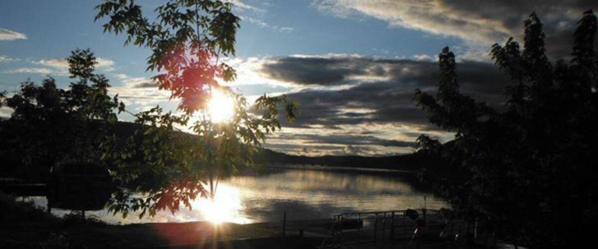 A sunset over a lake with a dock and trees.
