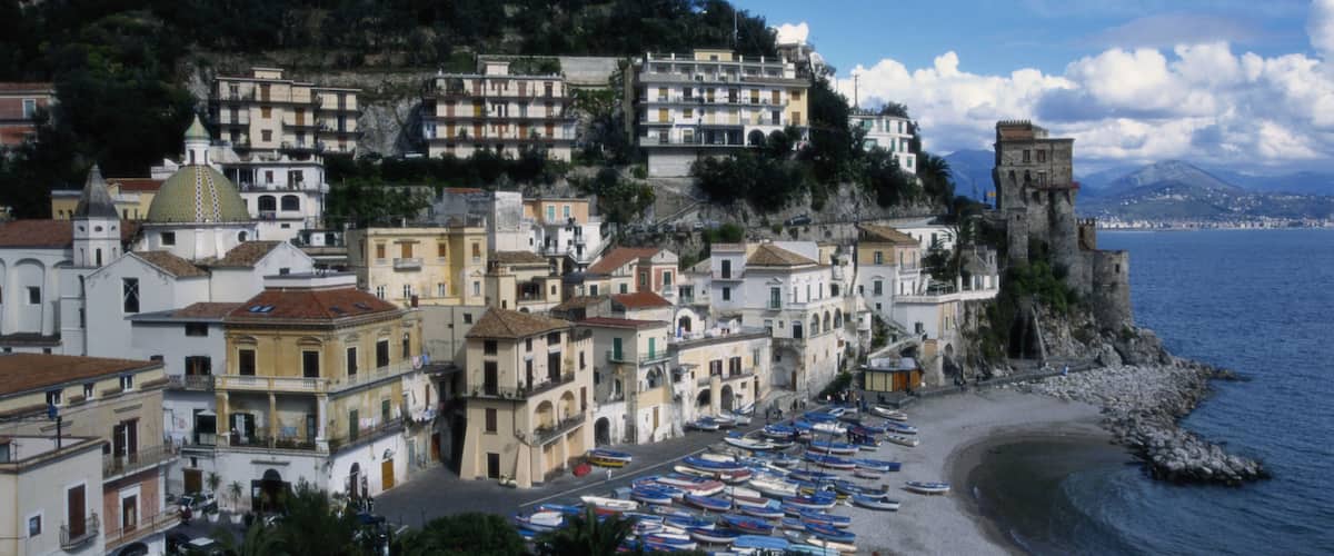 A coastal town with historic buildings, a rocky shoreline, and a clear blue sky.