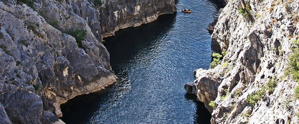 A river flowing through a rocky gorge with a bridge spanning across it.