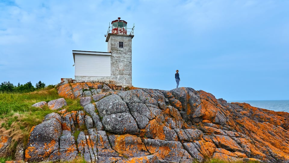 Woman sight seeing at Pea Point Lighthouse, Black's Harbor, New Brunswick, Canada.