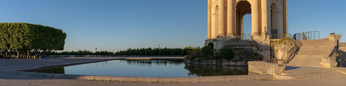 Scenic early morning panoramic view of the beautiful ancient water tower stone building and pool in historic Promenade du Peyrou garden, Montpellier, France