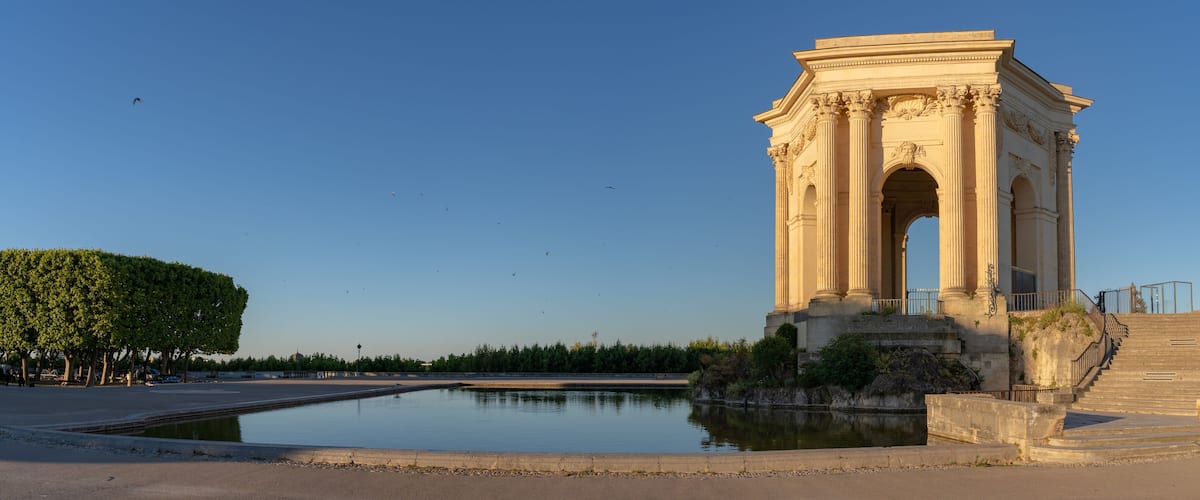 Scenic early morning panoramic view of the beautiful ancient water tower stone building and pool in historic Promenade du Peyrou garden, Montpellier, France