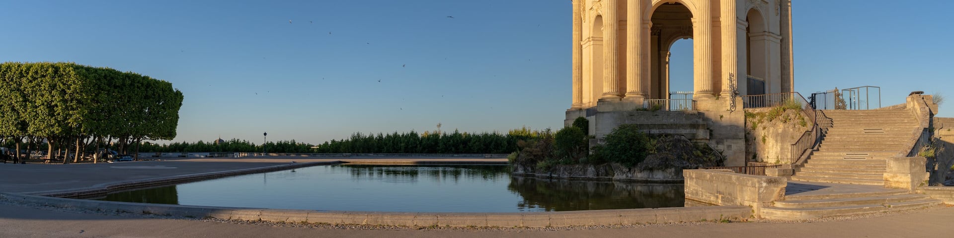 Scenic early morning panoramic view of the beautiful ancient water tower stone building and pool in historic Promenade du Peyrou garden, Montpellier, France