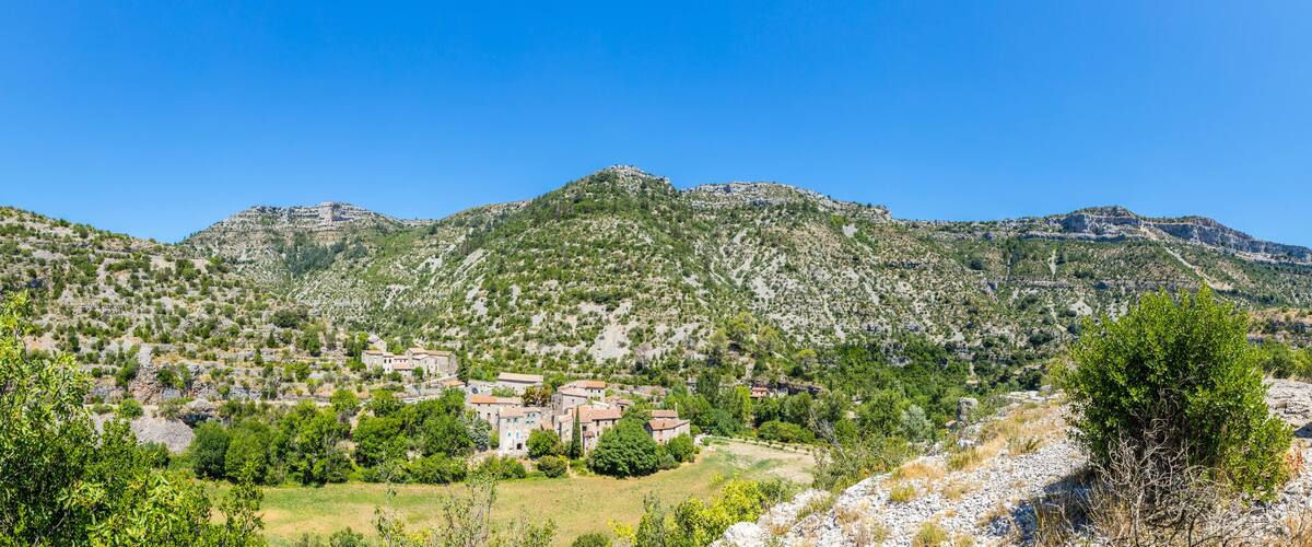 A mountainous landscape with a village and a statue.