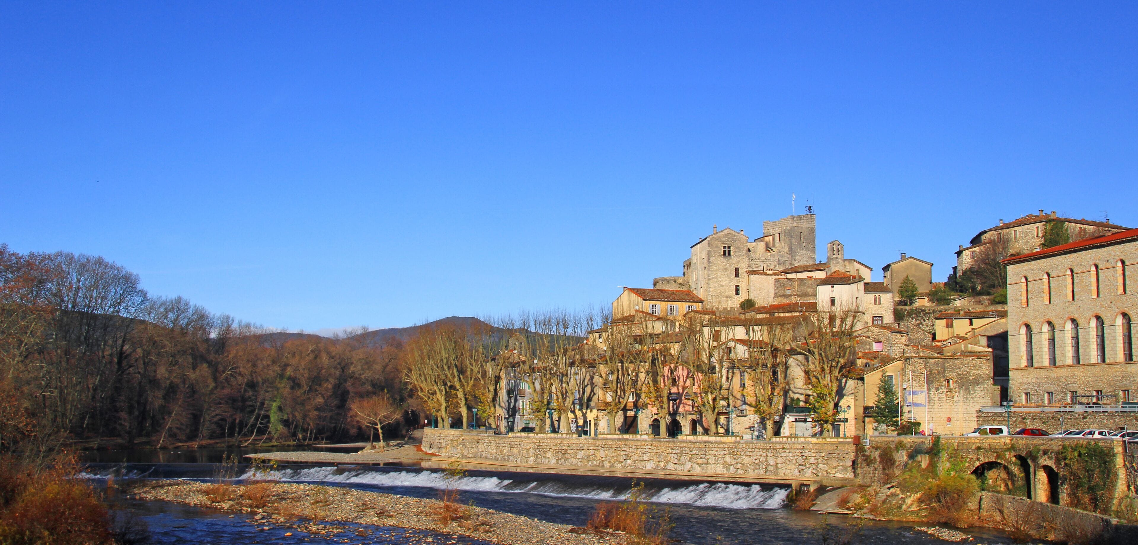 A historic town with a river, stone buildings, and a castle-like structure.