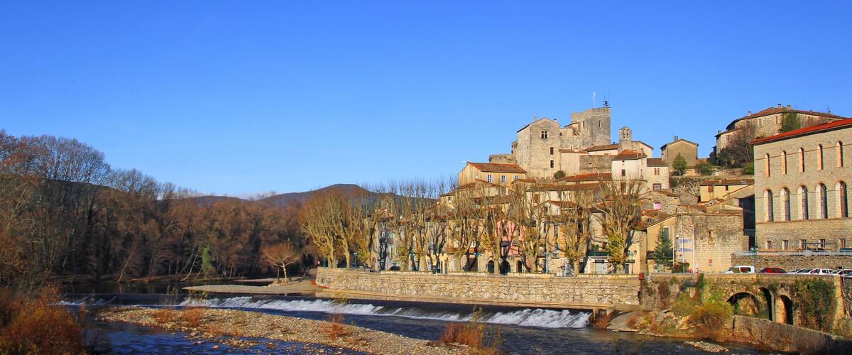 A historic town with a river, stone buildings, and a castle-like structure.