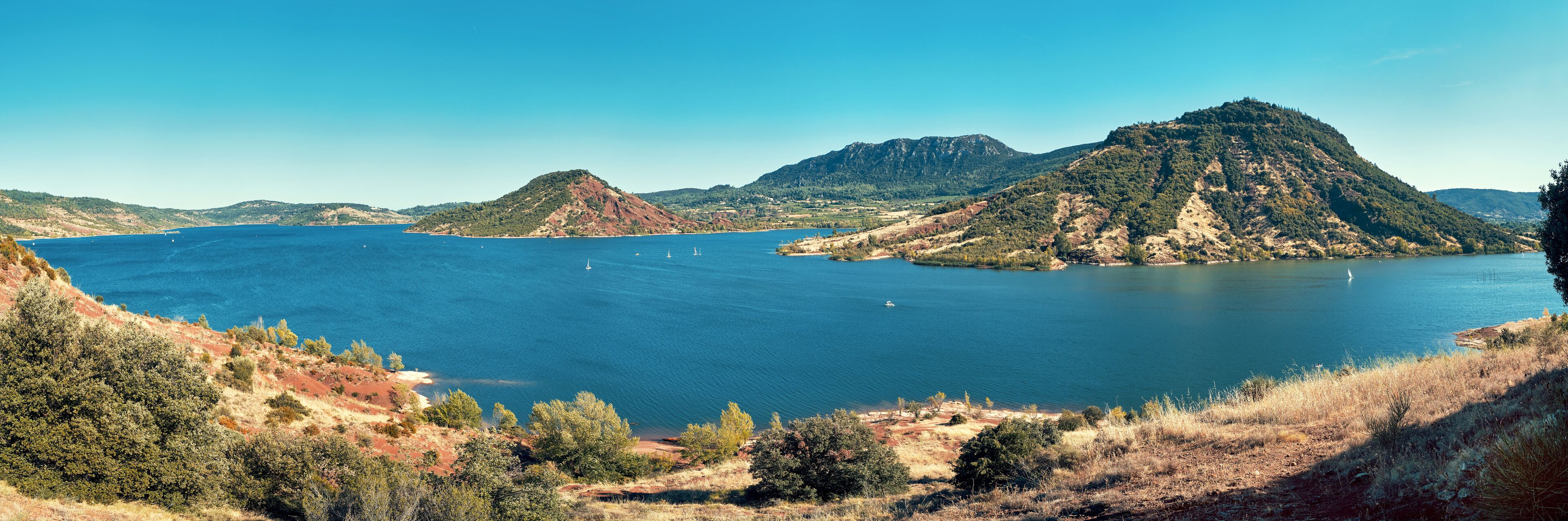 A coastal landscape with a large body of water, hills, and sparse vegetation.