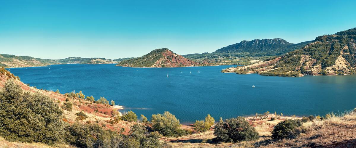 A coastal landscape with a large body of water, hills, and sparse vegetation.
