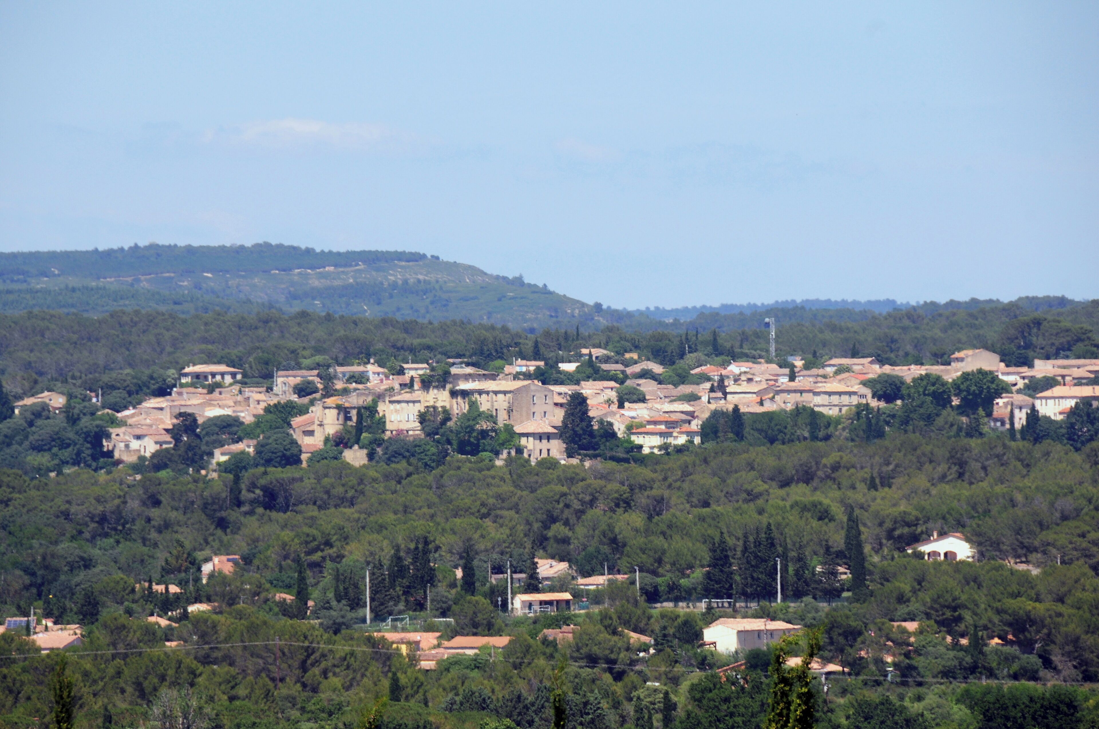A town nestled in a valley with dense forested hills in the background.