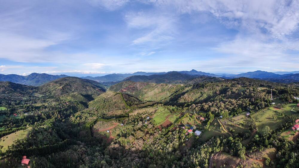 A mountainous landscape with scattered houses and dense forests.