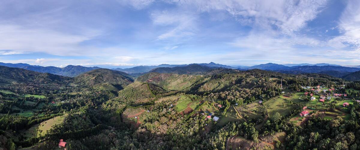A mountainous landscape with scattered houses and dense forests.